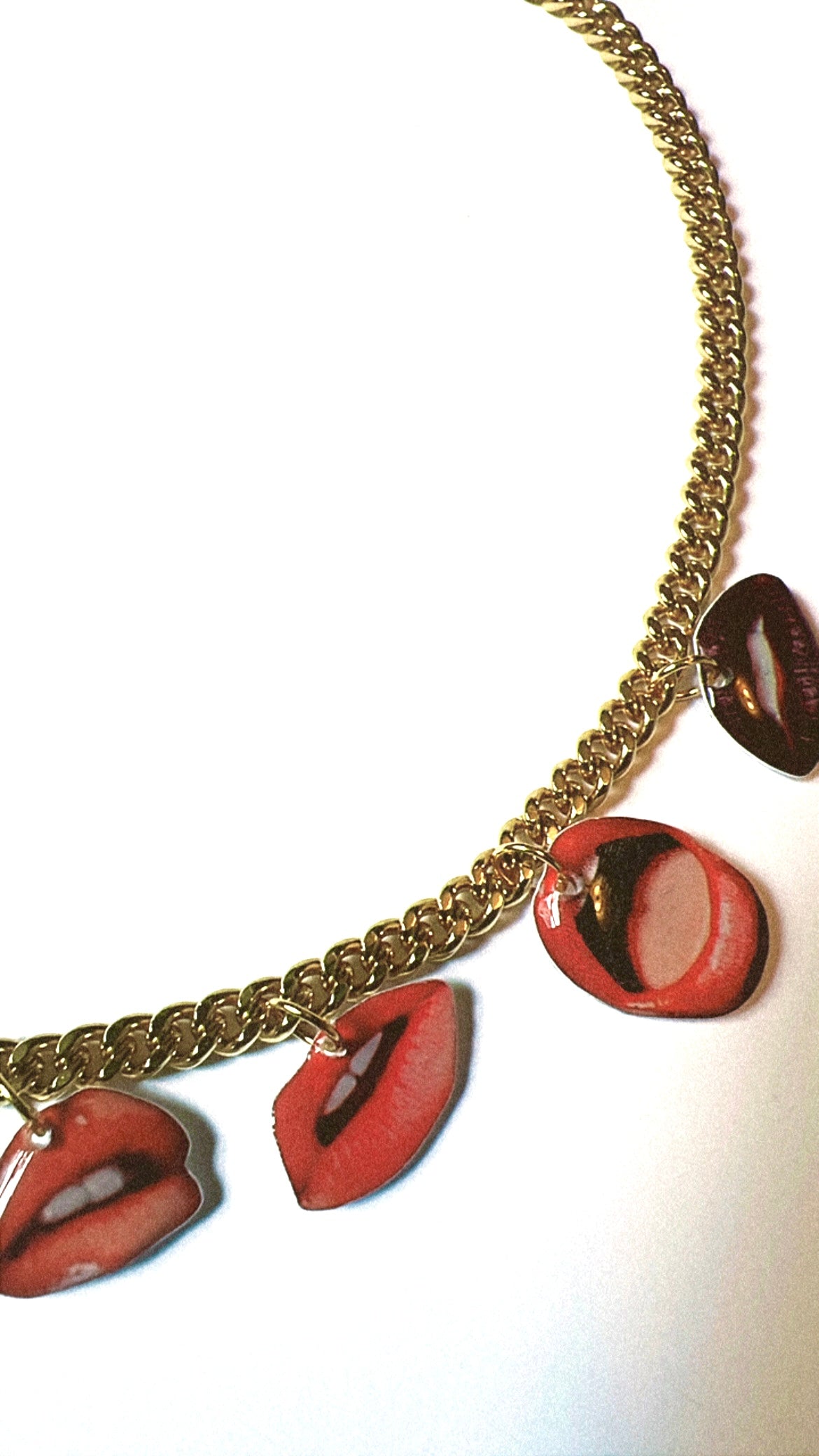 Necklace with lip-shaped pendants on a gold chain against a white background